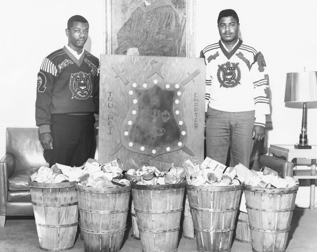 Omega Psi Phi members with baskets of canned food for charity.