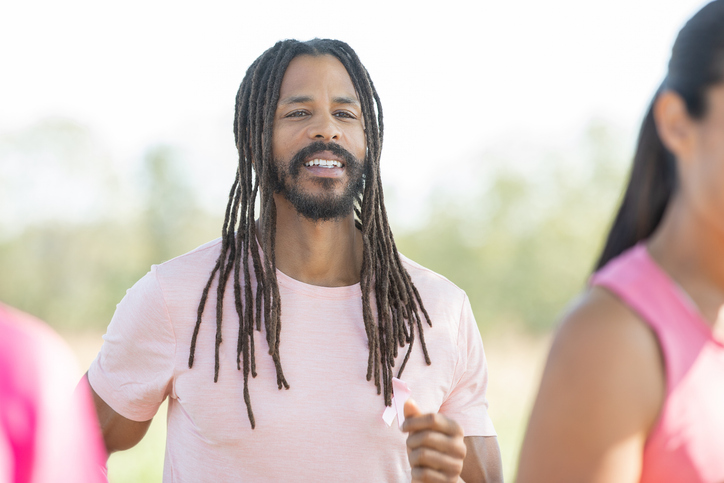 A Man in his midlife, radiating joy while running in a charity event for breast cancer awareness